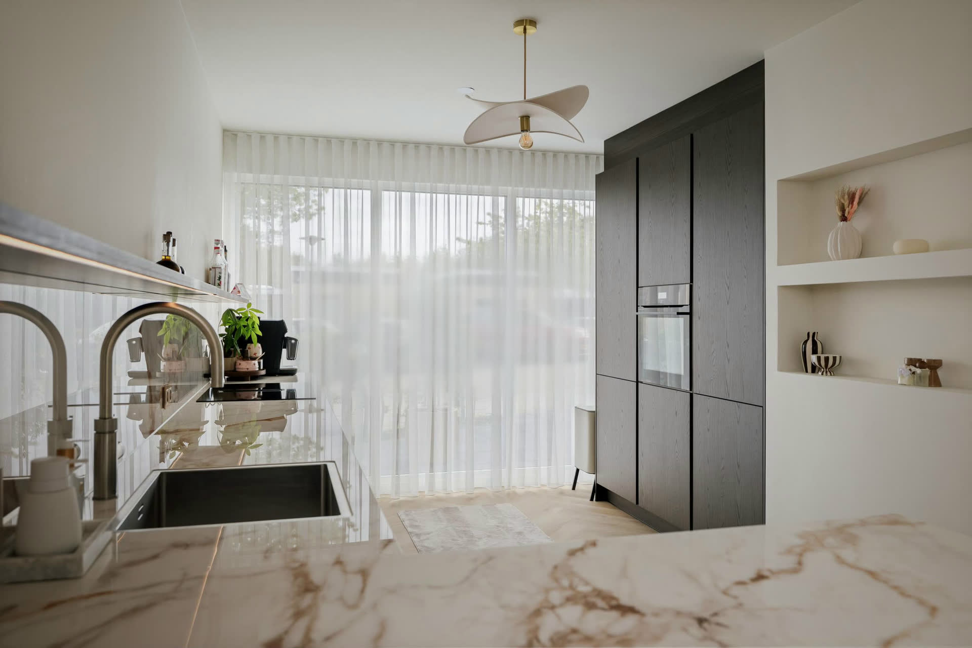 Een keuken in Deventer, door ons geleverd en geplaatst: hoge kastenwand in donker fineer met inbouwoven, een licht werkblad in marmerlook met kokendwaterkraan en open nissen in de wand.