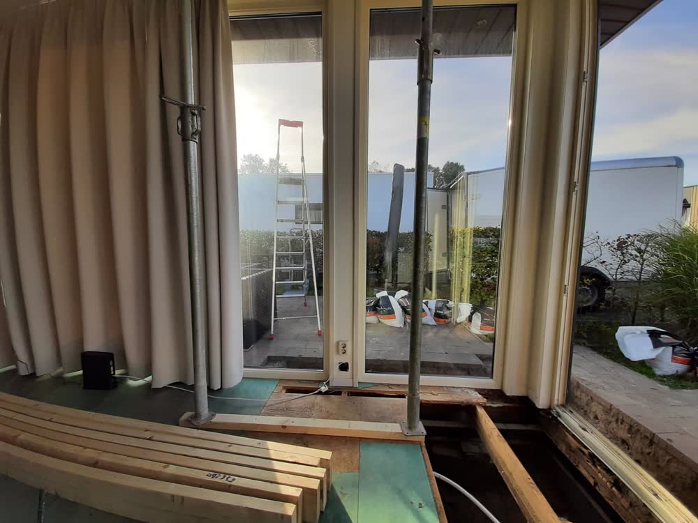 De vloer voor de schuifpui is opengemaakt; nieuwe balken liggen klaar